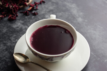Cup of hibiscus tea with dried hibiscus calyces on the side.
