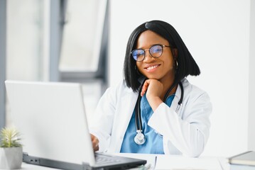 Young African-American doctor working on laptop in clinic