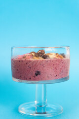 Mixed Berry Acai Smoothie Bowl on a light blue background. With granola, raisins and pink coconut chips. Copy space.