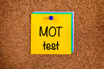 Reminder MOT test on yellow note paper with on cork board