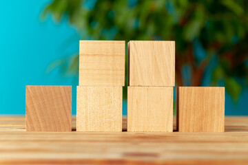Wooden blocks on desk against blurred plant background