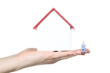 Female hand holding wooden house model with miniature man on white background