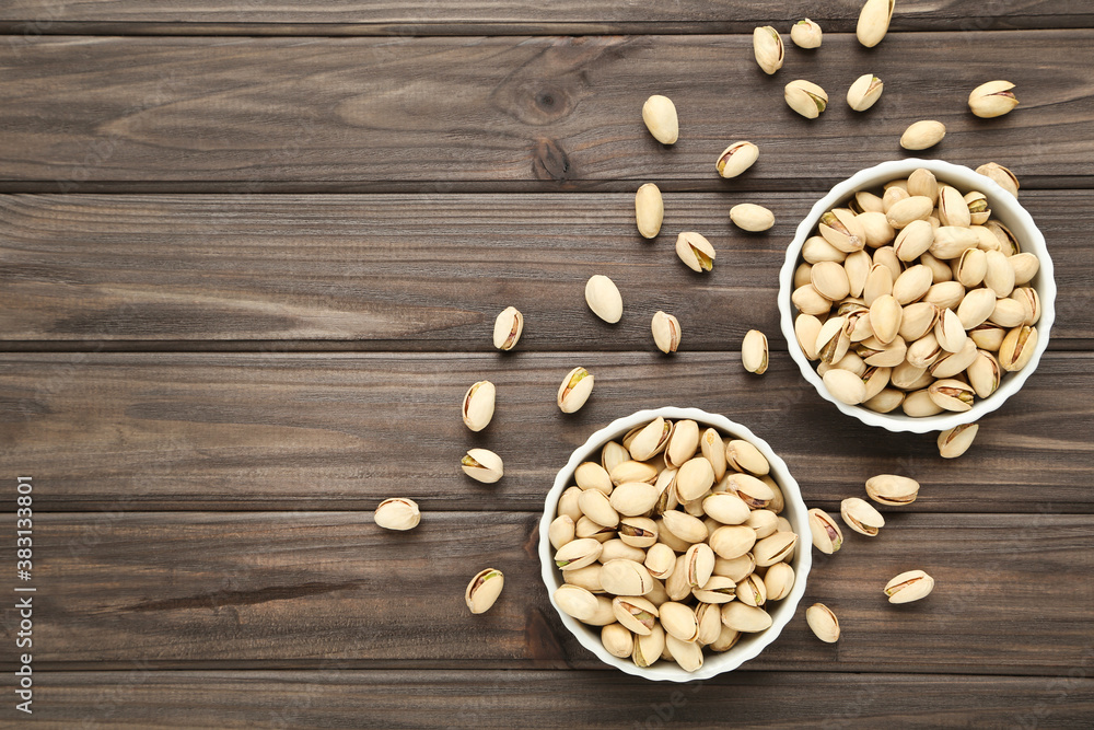 Poster tasty pistachios in bowls on wooden table