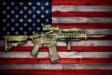 Camo painted army carbine on wooden surface with USA flag