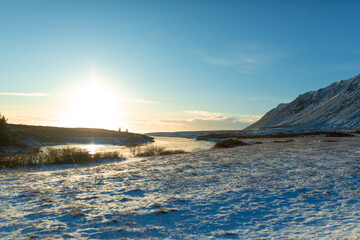 River on the plain in Iceland. The banks are covered with snow. Winter landscape, open spaces.
