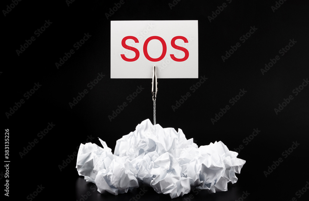 Poster close-up of crumpled paper on table with text sos