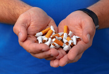 Male hands holding broken cigarettes close up