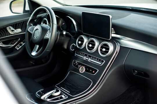 Modern car interior, black perforated leather, aluminum, details controls, leather steering wheel