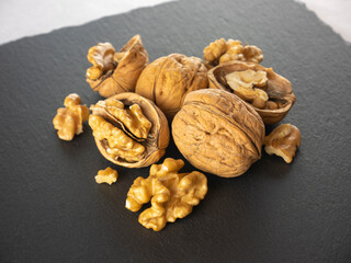 Walnuts kernels on dark background. Still life. Composition of nuts, whole with shell, opened, broken into pieces, and shelled. Healthy food ready for eating. Dried fruit snacks. Vitamins and omega 3