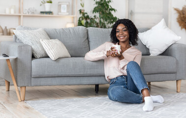 Dreamy African American Woman Unwinding At Home With Cup Of Coffee