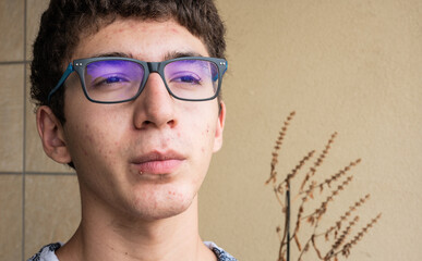 Close-up portrait on the skin of a young Caucasian boy in pubertal age: on his skin there are...