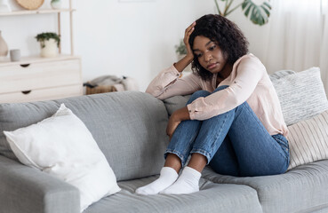 Depression Concept. Lonely upset african american woman sitting on couch at home