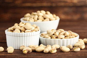 Pistachios in bowls on brown wooden table