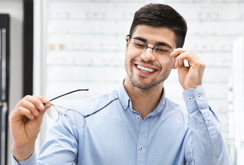 Portrait of handsome young man choosing spectacles