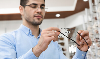 Portrait of serious young man choosing spectacles