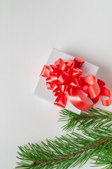 Greeting card with Gift box with bow and green pine branches on white background. New year or Christmas concept