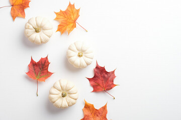Minimalist style autumn composition. Dry maple leaves and pumpkins on white background. Flat lay,...