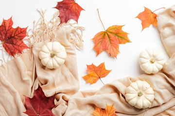 Autumn composition. Beige scarf, pumpkins, dry leaves on white background. Flat lay, top view. Autumn fashion, hygge, nordic style, concept