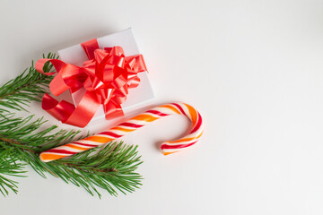Greeting card with Gift box with bow, candy and green pine branches on white background. New year or Christmas concept