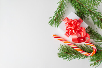 Greeting card with Gift box with bow, candy and green pine branches on white background. New year or Christmas concept