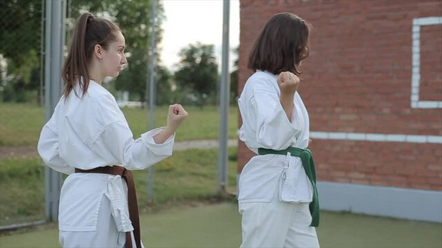 Martial arts female athletes practice karate techniques on the sports ground. Foreground. Close-up. Slow motion