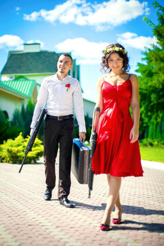 A guy with a girl in evening dresses with a gun and a suitcase of money