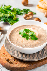 Mushroom cream soup. Champignon soup puree, toast and parsley on a gray concrete background. Tasty winter food, vegetarian food.