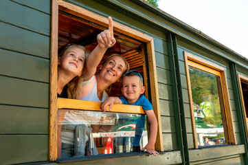 Happy smiling woman with her  children looking out from window while traveling together by train 