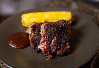 Tender Baby Back Ribs with a nice bark, sliced, served with corn and bbq sauce,  looking mouth watering delicious