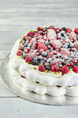 Meringue pavlova wreath cakes with whipped cream and fresh berries,
