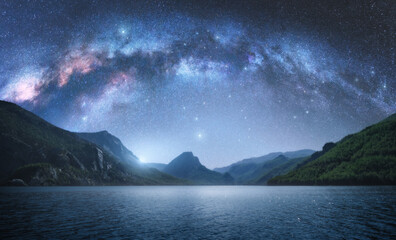 Arched Milky Way over the beautiful mountains and blue sea at night in summer. Colorful landscape...