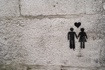 Fototapeta na wymiar Street graffiti of a man and a woman holding hands with a heart in the middle. A couple in a wall.