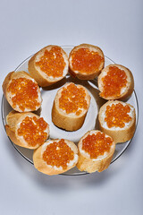 Sandwiches with butter and delicious red caviar on a plate on a white background