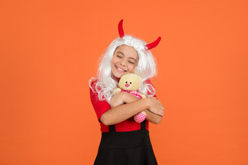 halloween devil kid in imp horns hold teddy bear toy for present, love the halloween