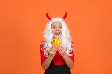 surprised child celebrate autumn holiday with traditional food. teenage girl in devil horns celebrate halloween. happy halloween. trick or treat. carnival festive costume of witch. kid with pumpkin