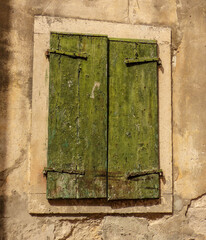 Stone window with old green shutters