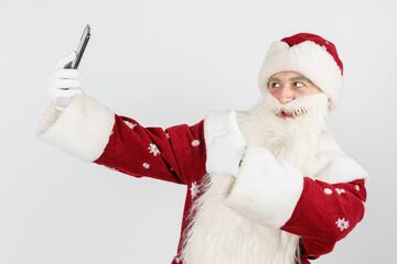 Santa Claus poses, makes a selfie on a mobile phone. Isolated background