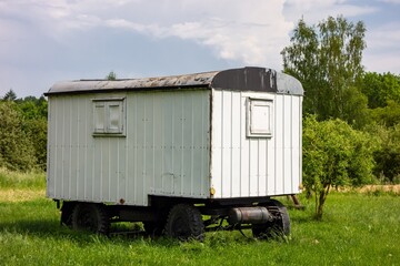 Very old white wooden caravan trailer parked on a grass