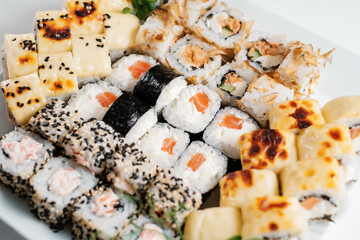 Top view of assorted sushi rolls on white plate.
