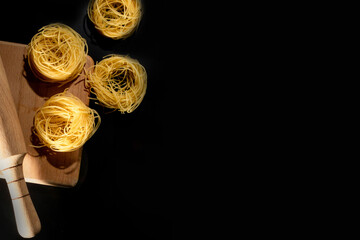 Rolled tagliatelle shape of italian pasta on black stone background . High quality photo