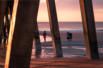 Couple Taking Sunrise Photos Under Pier 