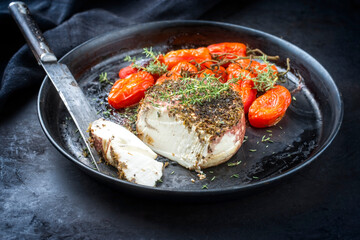 Traditional Italian Ricotta al forno cake with barbecue tomatoes and herbs offered as close-up on a rustic plate