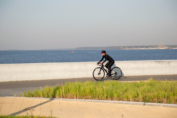 Obraz premium A woman rides a bicycle along the embankment. Riding a bicycle. Outdoor sports. Embankment of the Gulf of Finland Russia St. Petersburg.Cycling workout