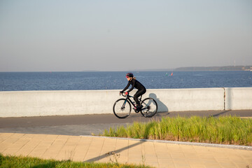 Obraz premium A woman rides a bicycle along the embankment. Riding a bicycle. Outdoor sports. Embankment of the Gulf of Finland Russia St. Petersburg.Cycling workout