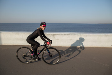 A woman rides a bicycle along the embankment. Riding a bicycle. Outdoor sports. Embankment of the Gulf of Finland Russia St. Petersburg.Sunrise Cycling Workout