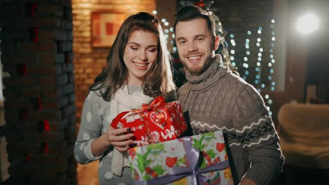 A young couple are holding christmas presents.