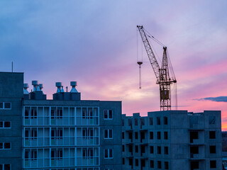 Fototapeta na wymiar high-rise crane in the construction of high-rise buildings in the city district, against the background of the sunset
