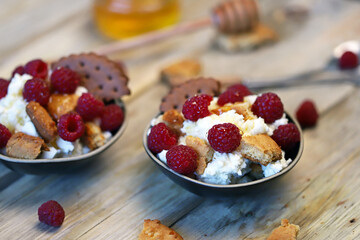 Mascarpone dessert with raspberries and biscuits in bowls.