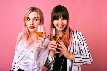 Indoor studio portrait of two happy best friends sisters women, wearing trendy black and white clothes, sue prized face.