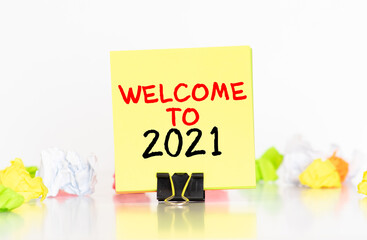 white paper with text Welcome 2021 on the blue background with a lot of another paper